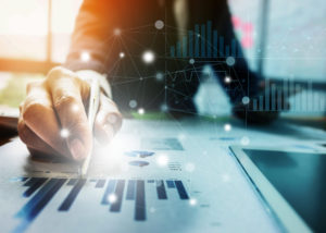 Close up Businessman hand holding pen and pointing at financial paperwork with financial network diagram.